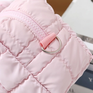 Detail shot of pink quilted fabric texture with silver D-ring and zipper on makeup bag