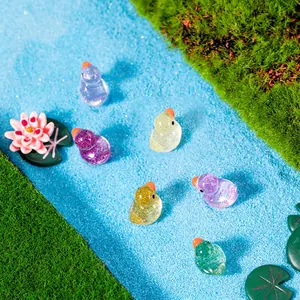 Mini resin ducks with glitter in micro landscape featuring colorful candy tones on blue sand