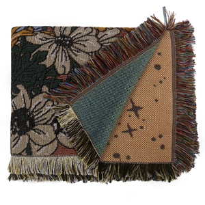 Dettaglio della coperta intrecciata boho con trama jacquard floreale e bordi con frange