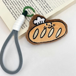 Detailed close-up of a plush bread-shaped cartoon keychain with braided strap and green ring