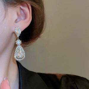 Detailed view of silver teardrop tassel earrings with sparkling crystals on model