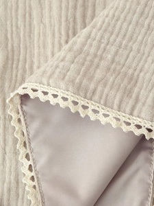 Close-up of textured muslin fabric with satin lining and delicate crochet lace trim