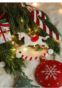 Close-up of hand-painted metal Christmas tree ornaments on festive green pine branches