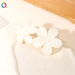 Close-up of white matte flower hair clip on a ceramic tray for minimalist hair styling