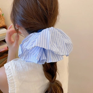 Nahaufnahme eines übergroßen blau-weiß gestreiften Stoff-Scrunchie am Pferdeschwanz