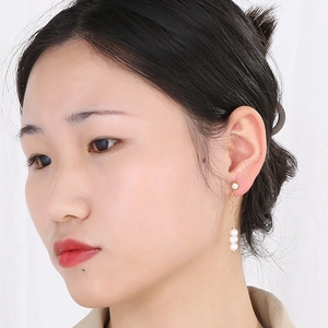 Vue détaillée des boucles d'oreilles dorées avec trois perles et une pierre ronde