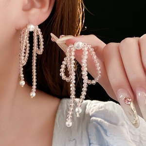 Detail view of long crystal tassel earrings with pink beads and white pearls on model
