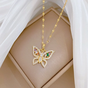 Detail of a gold butterfly necklace with colored stones resting on white silk fabric