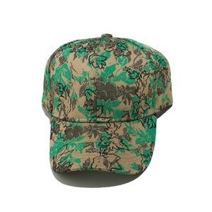 Detailed view of floral baseball cap featuring green leaf patterns on beige fabric
