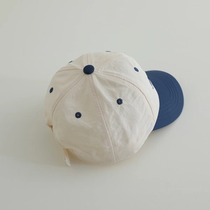 Detail of color-block kids baseball cap showing navy brim and cream quick-dry fabric