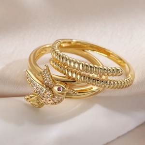 Detail of gold hummingbird ring with sparkling zircon stones and textured bands
