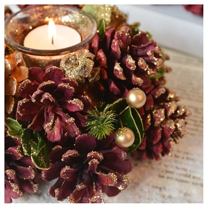 Macro shot of glass candle holder with pinecones, golden balls and green needles