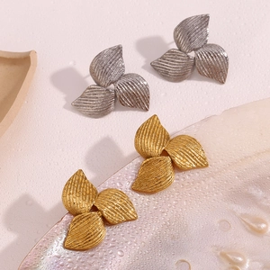 Macro detail of boomerang leaf earrings with textured finish in gold and silver