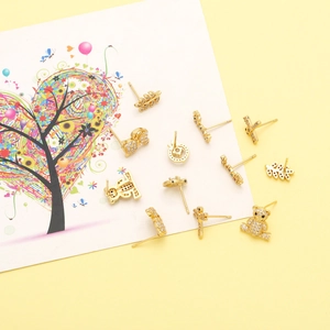 Macro detail of gold animal studs set including bear and bow with sparkling rhinestones
