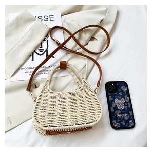 Flat lay of woven straw handbag with brown leather handles and adjustable strap