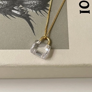 Detailed macro shot of a mini crystal lock pendant on a fine gold-plated chain