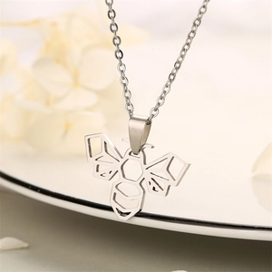 Detailed close-up of a silver origami bee pendant necklace on a soft white floral backdrop