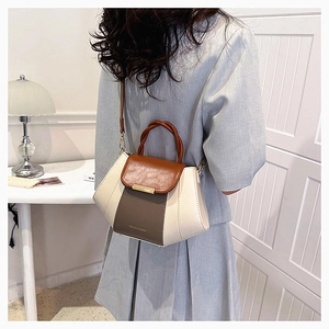 Detail view of contrast color handbag with woven handle and elegant golden metal buckle
