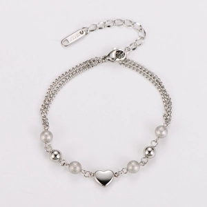 Detailed macro of stainless steel heart pendant and beads with 18KGP engraving
