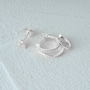Detail of s925 silver earring set with three-diamond stud and sparkling pavé hoop earrings