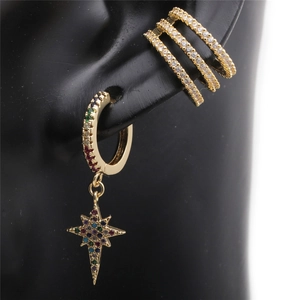 Detail of gold star drop earring and cubic zirconia ear cuff on a model ear