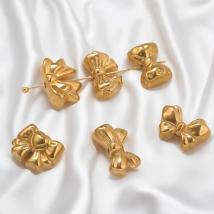 Macro detail of matte gold bow charms and heart beads for DIY jewelry making on silk