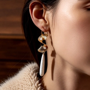 Detail of vintage gold twisted earrings with cubic zirconia and white teardrop pendant