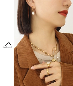 Detail of 18K gold plated stainless steel layered necklace and pearl earrings on model