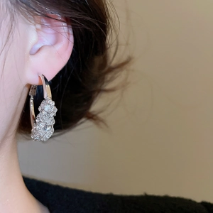 Detailed view of silver hoop earrings with shimmering zircons worn on ear