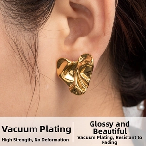 Detailed view of luxury gold heart stud earrings featuring fluid pleated metal texture
