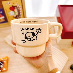 Minimalist beige ceramic coffee mug with cute cartoon dog pattern and hand-held view
