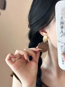 Detail of model wearing vintage wooden circular pendant earrings with golden metal studs