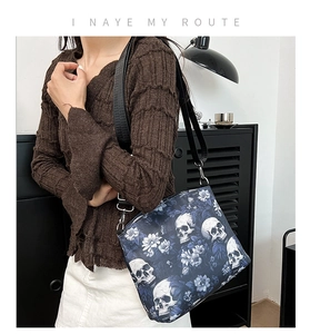 Detail of nylon tote bag with skull and floral print featuring black strap and metal buckle