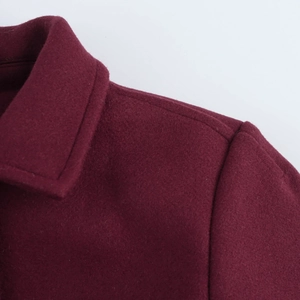 Macro detail of the lapel and shoulder on a burgundy wool blend coat with soft texture
