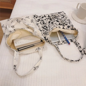 Detail view of cotton tote bags with black floral prints and beige inner lining