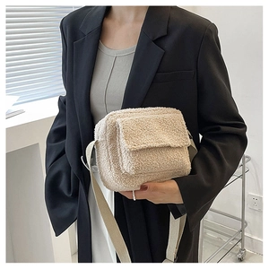 Detail of beige lamb wool crossbody bag with plush texture and fabric shoulder strap