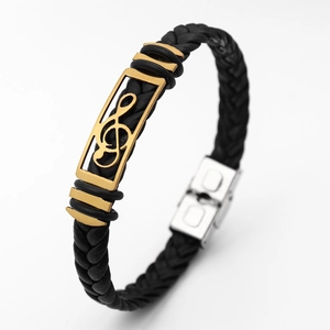 Close-up of black braided leather bracelet with golden music note metal accent