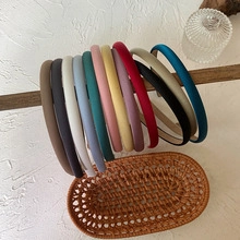 Collection of slim fabric-wrapped headbands in multiple colors hanging on a wooden rod