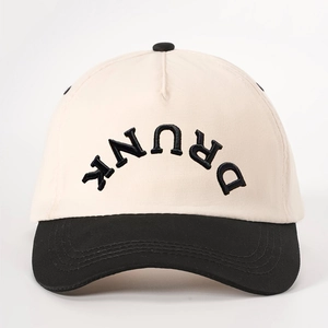 Detailed close-up of DRUNK embroidered lettering on a two-tone beige and black baseball cap
