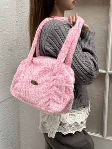 Vue latérale d'un sac à main en peluche rose léopard porté par un mannequin en hiver