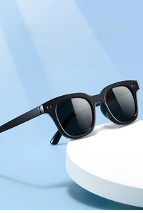 Close-up of classic black square sunglasses featuring metal dot accents on a blue background
