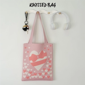 Detailed close-up of pink knitted tote bag with heart patterns and soft fabric texture