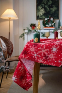 Detail of red Christmas tablecloth with white snowflakes and a green scented candle