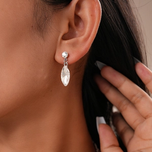 Close-up of elegant silver leaf earring with marquise crystal on a female model