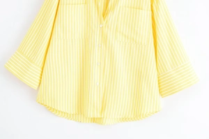Detail of yellow and white striped V-neck shirt showing front pockets and cuff texture