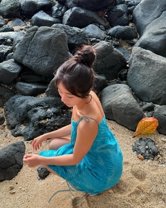 Close-up of blue mosaic snake print chiffon dress on a beach with volcanic rocks