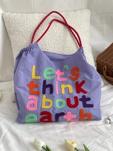 Detail of lilac canvas tote with colorful towel embroidery and red braided handles