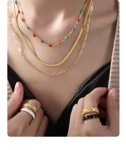 Gros plan du collier triple épaisseur en acier titane avec perles et bagues dorées