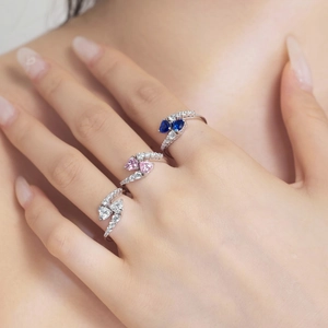 Detailed view of elegant silver rings with blue pink and white heart stones on a finger