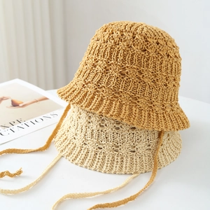 Dettaglio di cappelli a secchiello in paglia intrecciata caramello e beige con lacci